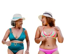 Senhoras sorrindo enquando aproveitam uma praia utilizando peças confeccionadas por JC dias